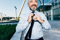 Mature businessman outdoors, straightening his tie — Stock Photo