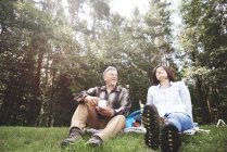 Couple d'âge mûr se détendre sur l'herbe avec la forêt en arrière-plan — Photo de stock