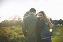 Rear view of young couple strolling arm in arm in field — Stock Photo