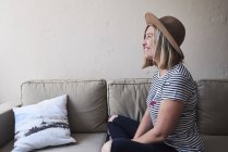 Frau sitzt auf Sofa, lächelt, Seitenblick — Stockfoto