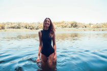 Ritratto di donna in costume da bagno in piedi in acqua e sorridente — Foto stock