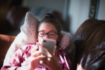 Mädchen entspannt sich auf Sofa und schaut aufs Smartphone — Stockfoto