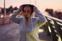 Curvaceo giovane donna ottenere felpa sul ponte pedonale al crepuscolo — Foto stock