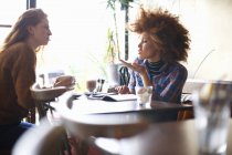 Вид збоку друзів-жінок, які розмовляють у кафе — стокове фото