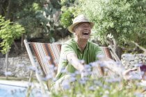 Man in garden sitting in deck chair laughing — Stock Photo