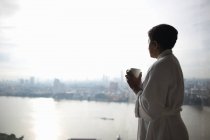 Woman holding cup and looking at view of city, Bangkok, Krung Thep, Thailand, Asia — Stock Photo