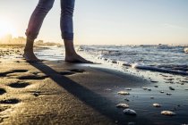Legs of barefooted woman standing at water's edge on beach, Riccione, Emilia-Romagna, Italy — Stock Photo