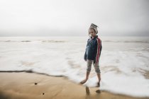 Porträt eines Jungen, der am Strand steht und in die Kamera blickt — Stockfoto