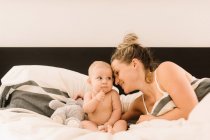 Donna sdraiata a letto con bambina — Foto stock