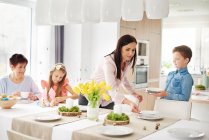 Woman and family preparing place settings at easter dining table — Stock Photo