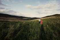 Rückansicht des Paares beim Händchenhalten und Spazierengehen auf Feldern — Stockfoto