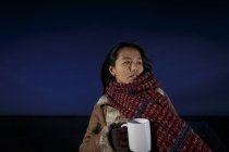 Young woman wrapped in scarf on beach at night — Stock Photo