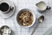 Cereal with dried fruit, coffee and milk jug, overhead view — Stock Photo