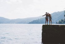 Dos jóvenes mirando desde el muelle, Lago de Como, Lombardía, Italia - foto de stock