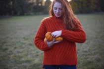 Young woman holding pumpkins in rural setting — Stock Photo