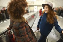 Two young women standing on moving escalator — Stock Photo