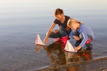 Two young girls floating toy boats on water — Stock Photo