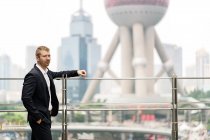Young businessman leaning on handrail at Shanghai financial center, China — Stock Photo