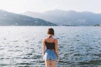 Вид сзади на молодую женщину на берегу озера Комо, Ломбардия, Италия — стоковое фото