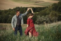 Romantic pregnant couple dancing in field — Stock Photo