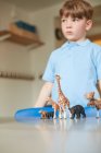 Schoolboy with toy animals in classroom at primary school — Stock Photo