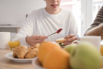 Обрезанный снимок молодой женщины и парня с круассанами за завтраком — стоковое фото