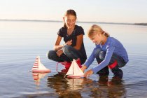 Дві молоді дівчата плавають іграшкові човни на воді — стокове фото