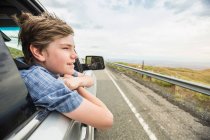 Boy on road trip leaning out of car window — Stock Photo