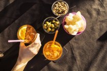 Overhead view of sidewalk cafe table with woman's hand holding aperitif, Riccione, Emilia-Romagna, Italy — Stock Photo