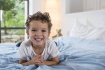 Boy lying on bed and smiling at camera — Stock Photo