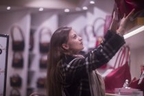 Женщина берет сумку у витрины магазина — стоковое фото