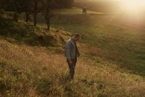 Середній дорослий чоловік стоїть на схилі пагорба на заході сонця — стокове фото