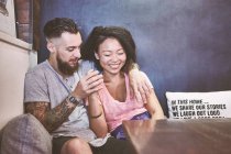 Multi ethnic hipster couple in cafe laughing, Shanghai French Concession, Shanghai, China — Stock Photo