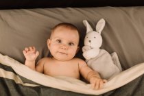 Ritratto di bambina sdraiata a letto con peluche — Foto stock