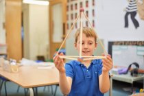 Grundschüler hält Strohpyramide aus Plastik im Klassenzimmer hoch — Stockfoto