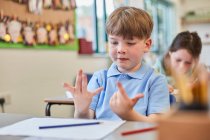 Школьник считает пальцами на уроке в начальной школе — стоковое фото