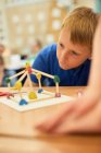 Primary schoolboy looking at plastic straw model on classroom desks — Stock Photo