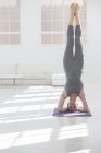 Frau zu Hause beim Kopfstand in Yogaposition — Stockfoto