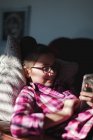 Дівчина розслабляється на дивані і дивиться на смартфон — стокове фото