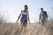 Jovem casal caminhando através de grama longa, Las Palmas, Ilhas Canárias, Espanha — Fotografia de Stock