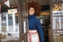 Portrait of small business owner in cafe doorway smiling at camera — Stock Photo