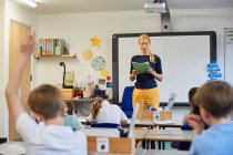 Schoolboy with hand raised in classroom lesson at primary school — Stock Photo