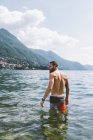 Вид сзади на молодого мужчину в озере Комо, Ломбардия, Италия — стоковое фото