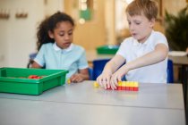Estudante e menina construindo blocos de brinquedo em sala de aula na escola primária — Fotografia de Stock