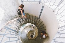 Vista de ángulo alto de tres amigos que bajan en escalera de caracol, Como, Lombardía, Italia - foto de stock