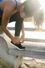 Молодая женщина тренируется на пляже и завязывает тренерские шнурки — стоковое фото