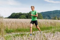 Joven corredor masculino corriendo por la pista de tierra rural - foto de stock