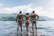 Rear view of three friends standing in lake Como, Como, Lombardy, Italy — Stock Photo
