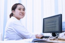 Жінка-лікар використовує комп'ютер в кабінеті — стокове фото