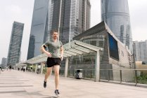 Hombre joven corriendo en el centro financiero de Shanghai, Shanghai, China - foto de stock